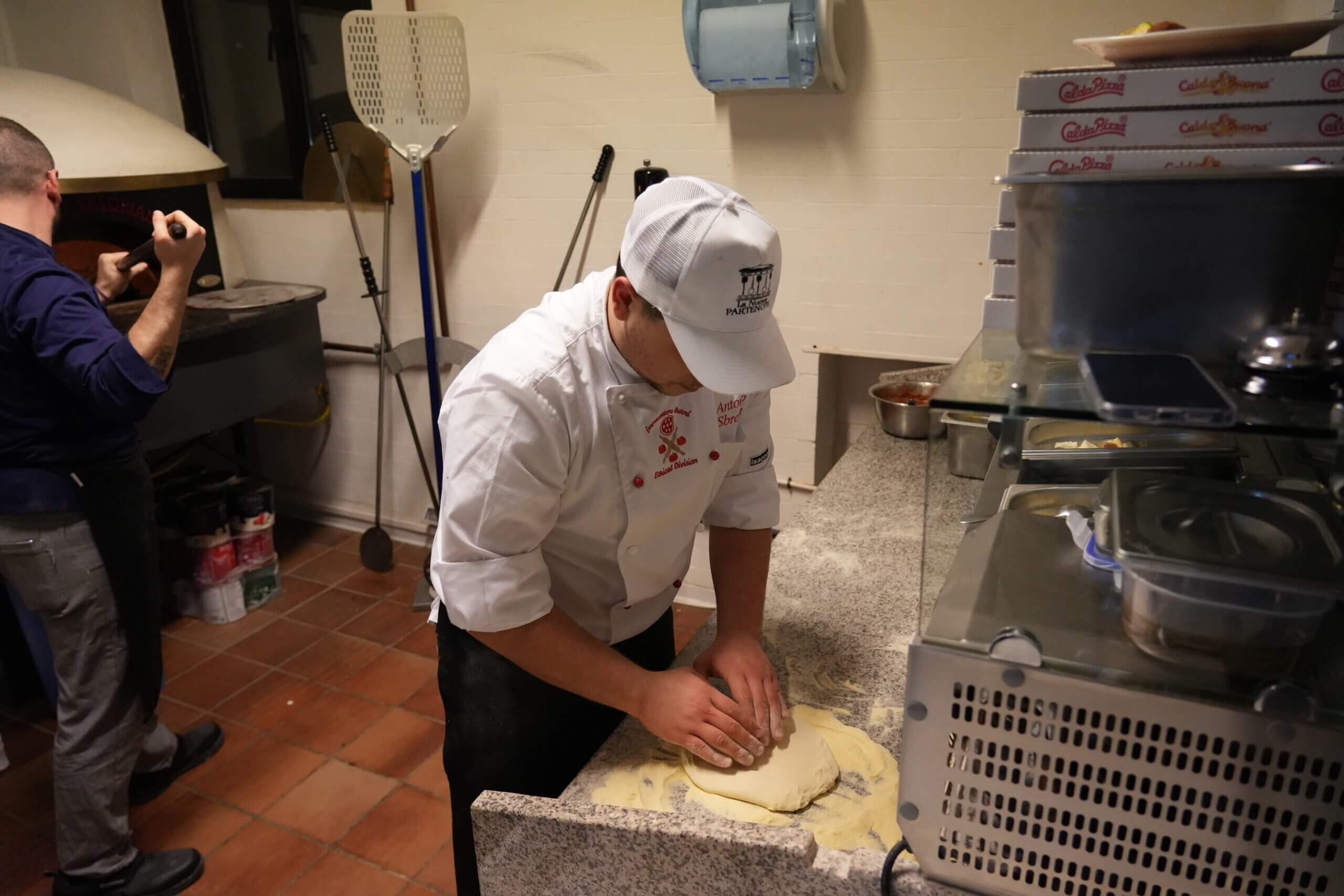 Pizzaiolo che impasta una pizza